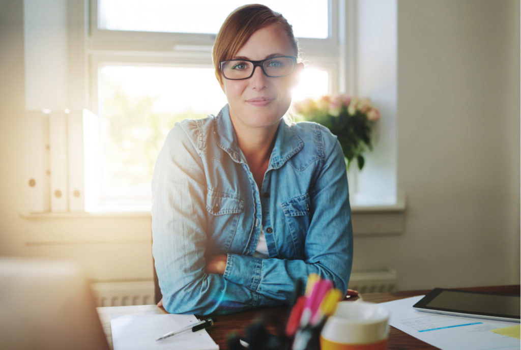 Woman in glasses smiling with new business ideas written on paper on her desk