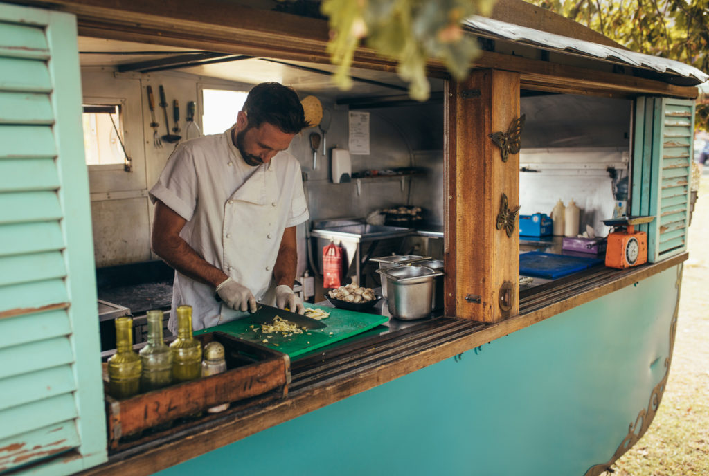 A small business owner chopping vegetables after expanding his operation with a small business loan