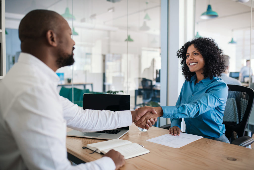 Woman shakes man's hand after being hired